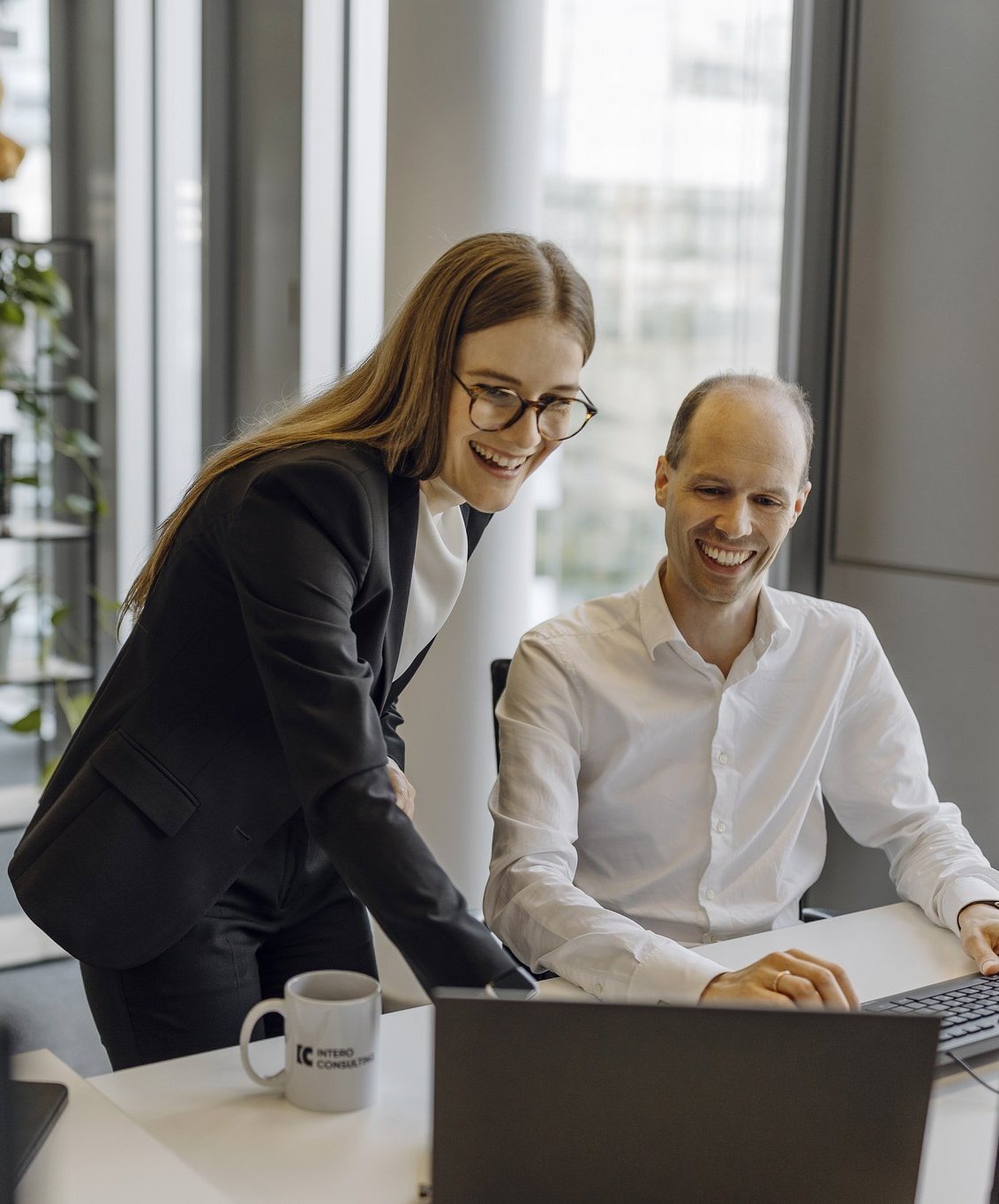 Ein Partner und eine Managerin sehen sich etwas auf einem Laptop an.