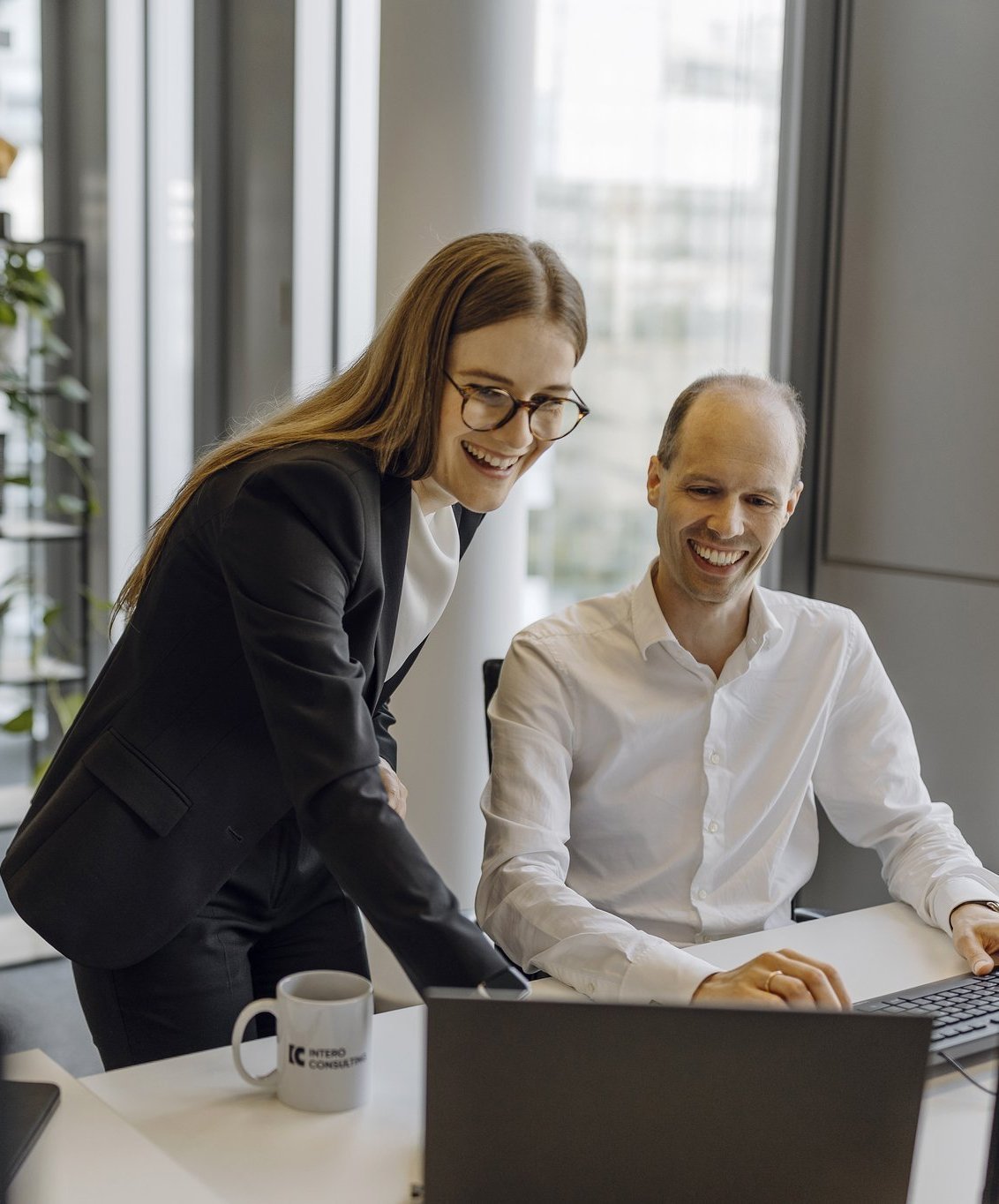 Ein Partner und eine Managerin sehen sich etwas auf einem Laptop an.