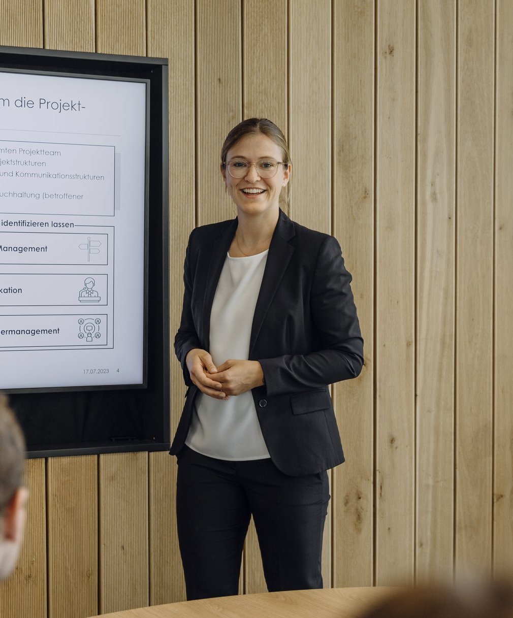 Eine Consultant erklärt ihrem Team die Strategie an einem Bildschirm.