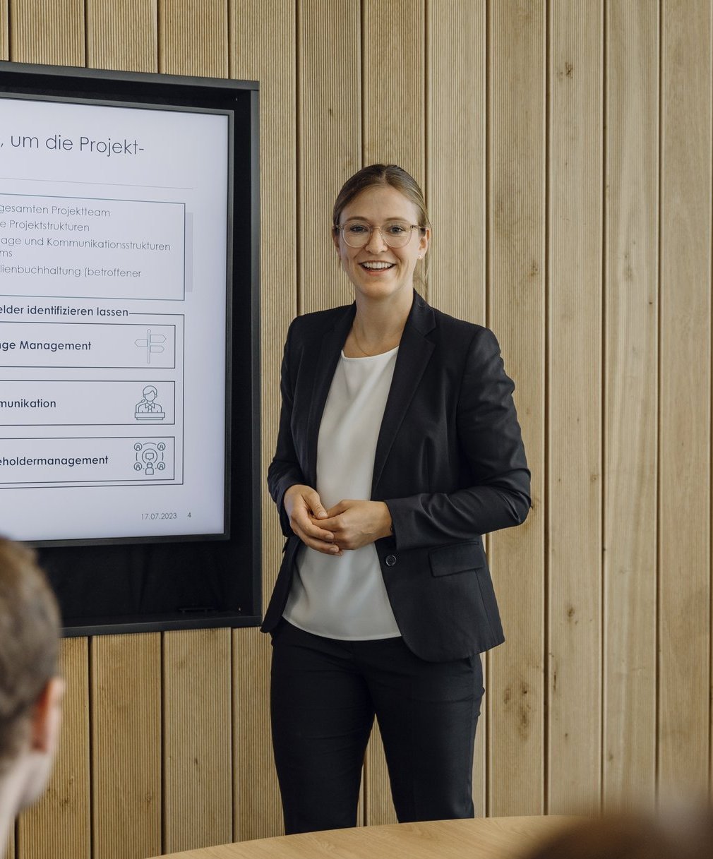 Eine Consultant erklärt ihrem Team die Strategie an einem Bildschirm.