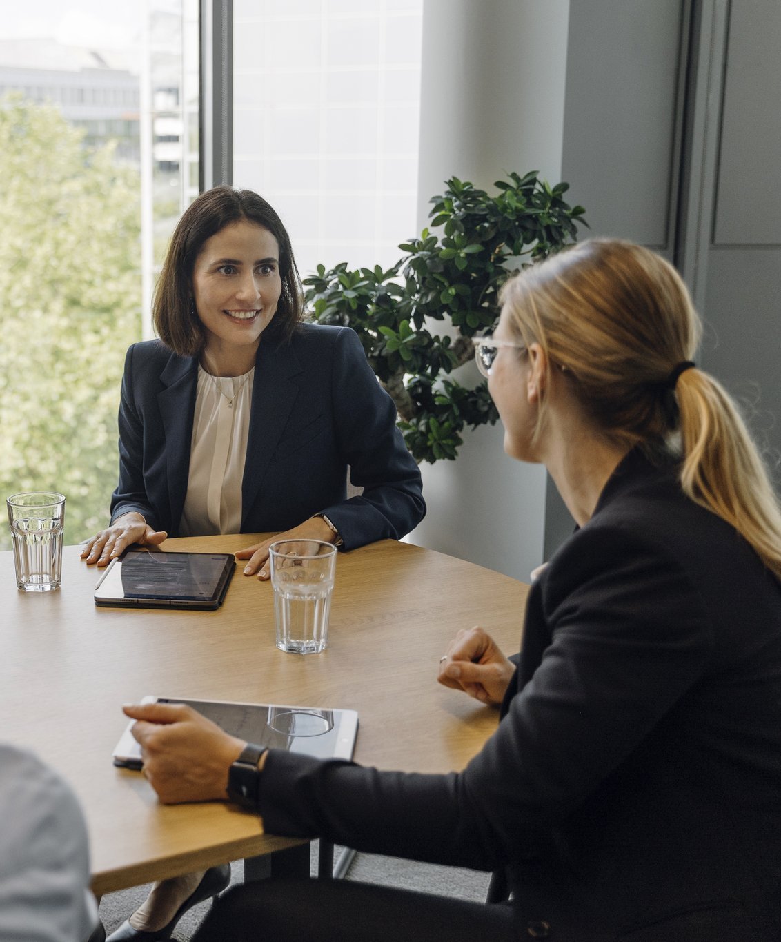 Eine Gruppe von Consultants und eine Partnerin sitzen an einem Meetingtisch.
