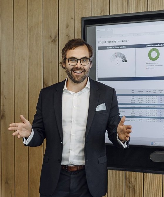 Ein Consultant stellt seinem Team eine Präsentation auf einem Smart Hub vor.vor.