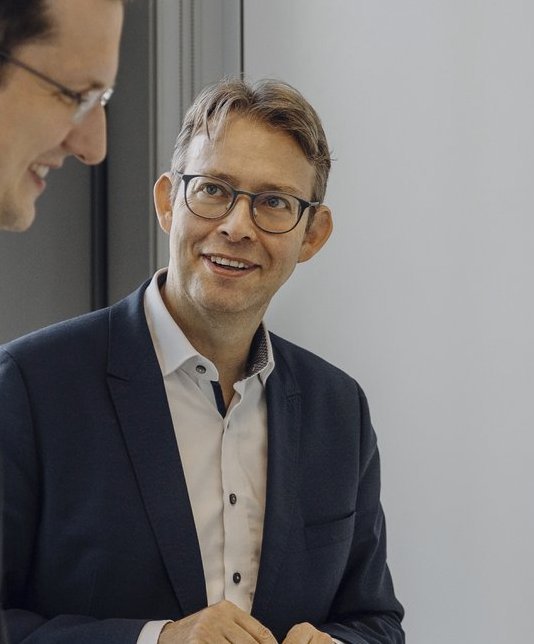 Zwei Consultants besprechen sich an ihrem Laptop.
