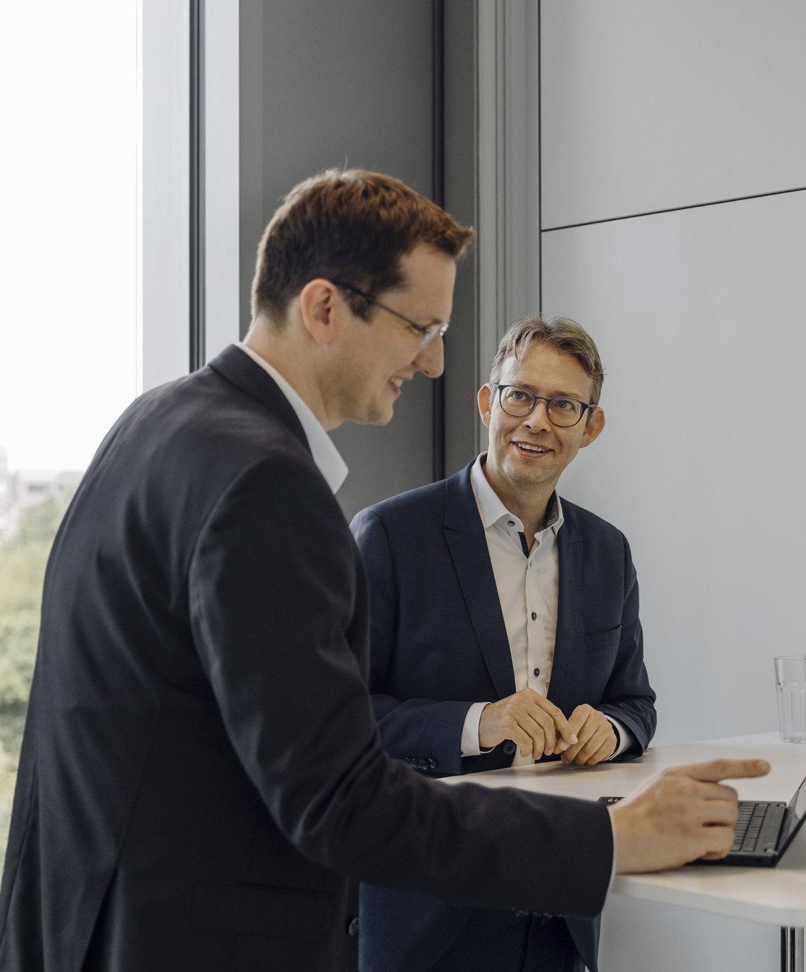 Zwei Consultants besprechen sich an ihrem Laptop.