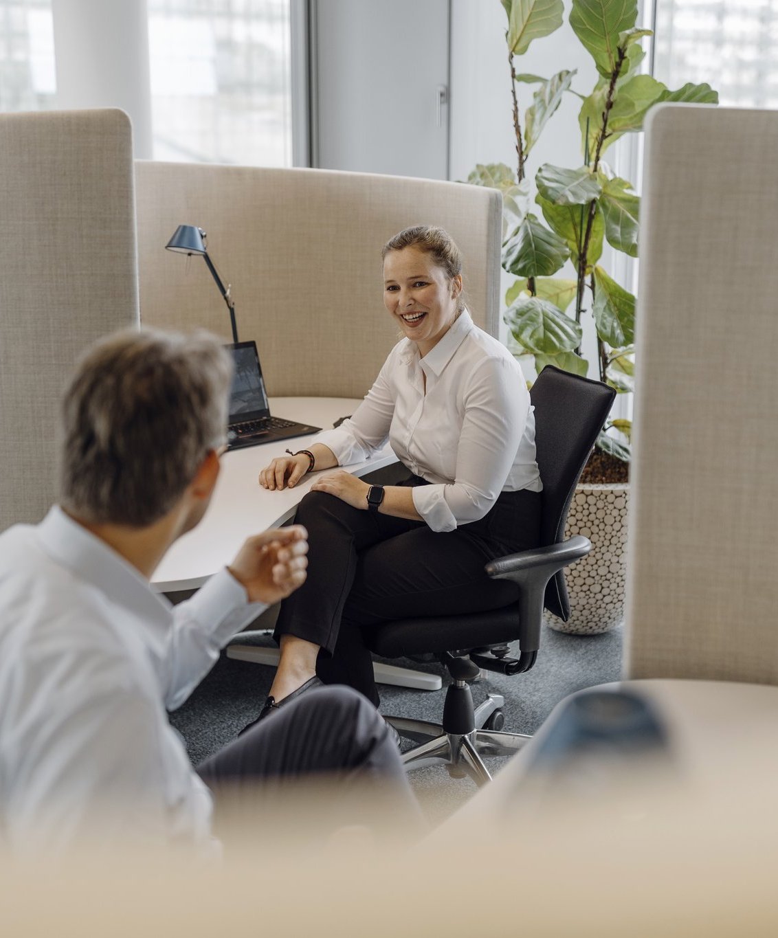 Zwei Consultants beraten sich über ihre Arbeitsplätze hinweg.