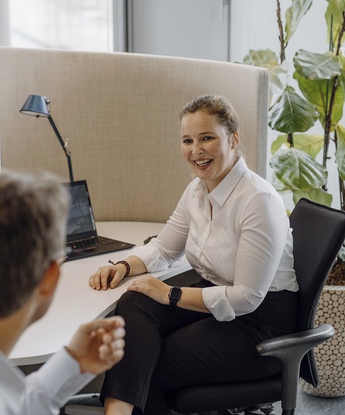 Zwei Consultants beraten sich über ihre Arbeitsplätze hinweg.